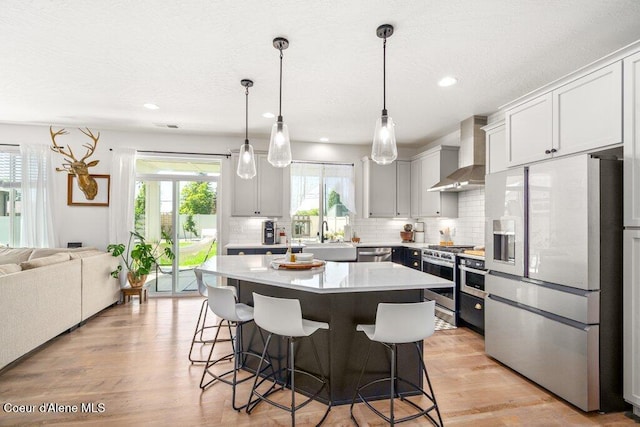 1839 N Skagit Dr, Post Falls, ID 83854 - kitchen featuring stainless steel appliances, wall chimney range hood, a breakfast bar, tasteful backsplash, and recessed lighting
