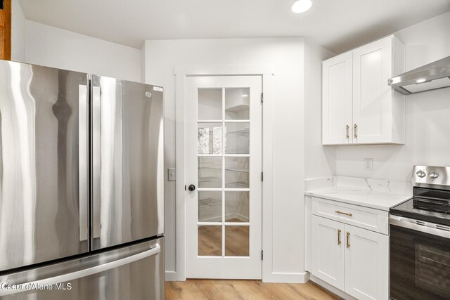 28729 Ramsey Rd, Athol, ID 83801 - kitchen with appliances with stainless steel finishes, white cabinets, light stone counters, wall chimney range hood, and recessed lighting