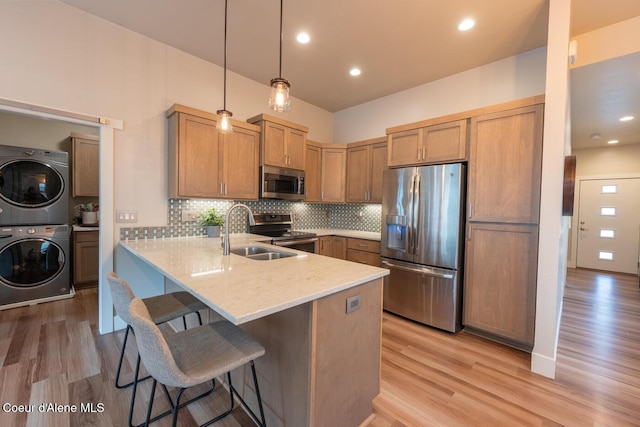 3304 N Rosalia Rd, Coeur Dalene, ID 83814 - kitchen featuring appliances with stainless steel finishes, stacked washer and clothes dryer, a peninsula, a breakfast bar area, and light stone countertops