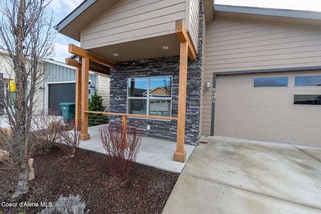 3304 N Rosalia Rd, Coeur Dalene, ID 83814 - view of exterior entry with stone siding, an attached garage, concrete driveway, and covered porch