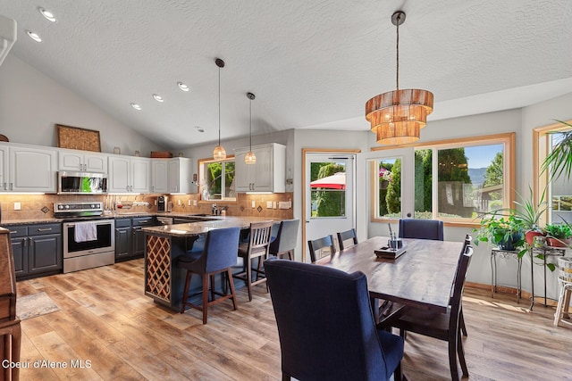 2042 W Heavenly Star Ct, Post Falls, ID 83854 - dining area featuring a textured ceiling, light wood finished floors, a chandelier, lofted ceiling, and plenty of natural light