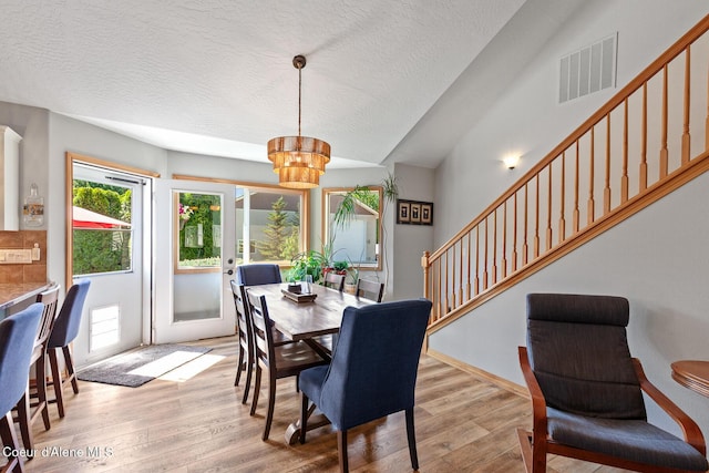 2042 W Heavenly Star Ct, Post Falls, ID 83854 - dining space featuring stairway, plenty of natural light, wood finished floors, a chandelier, and a textured ceiling