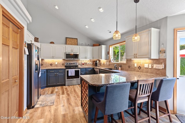 2042 W Heavenly Star Ct, Post Falls, ID 83854 - kitchen featuring stainless steel appliances, a peninsula, white cabinetry, a textured ceiling, and light wood finished floors