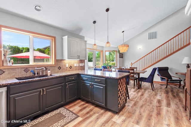 2042 W Heavenly Star Ct, Post Falls, ID 83854 - kitchen with white cabinetry, light wood-type flooring, a peninsula, tasteful backsplash, and vaulted ceiling