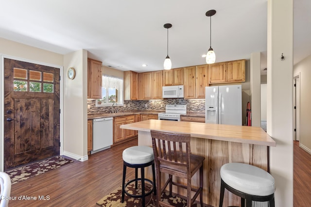 2042 W Heavenly Star Ct, Post Falls, ID 83854 - kitchen featuring white appliances, dark wood-style floors, decorative backsplash, a breakfast bar, and recessed lighting