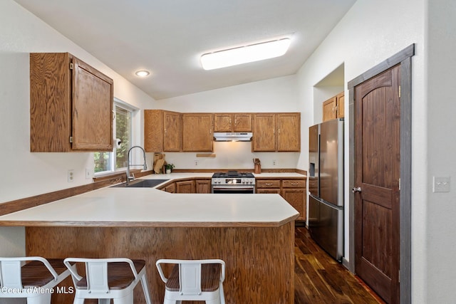 7386 W Sunrise Ct, Rathdrum, ID 83858 - kitchen with appliances with stainless steel finishes, a peninsula, vaulted ceiling, dark wood-style flooring, and brown cabinets