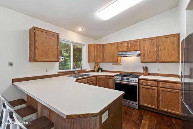 7386 W Sunrise Ct, Rathdrum, ID 83858 - kitchen with appliances with stainless steel finishes, under cabinet range hood, a peninsula, vaulted ceiling, and brown cabinetry