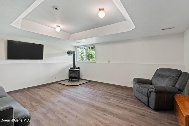 7386 W Sunrise Ct, Rathdrum, ID 83858 - living area featuring a raised ceiling, a wood stove, and wood finished floors