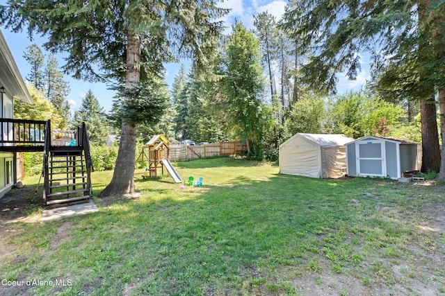 7386 W Sunrise Ct, Rathdrum, ID 83858 - fenced yard featuring a storage unit, stairway, a playground, a wooden deck, and view of wooded area