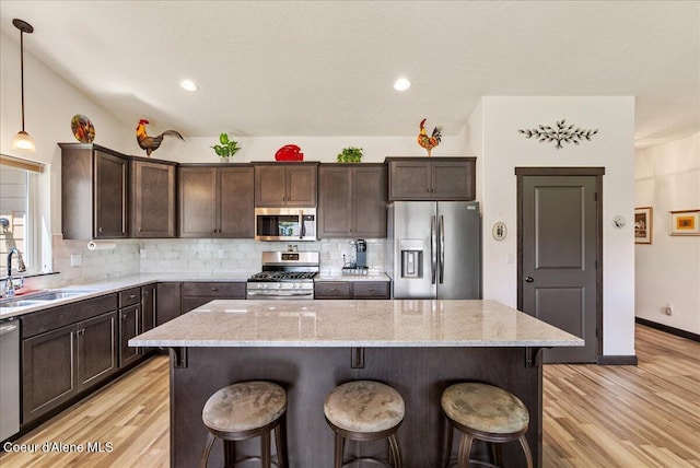 2636 N Wrenley Ln, Post Falls, ID 83854 - kitchen with appliances with stainless steel finishes, light wood-style floors, dark brown cabinetry, a kitchen breakfast bar, and recessed lighting