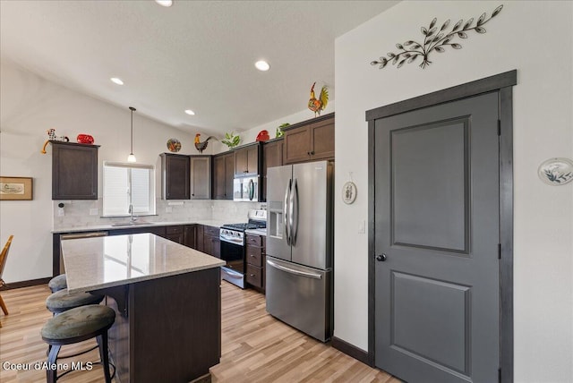 2636 N Wrenley Ln, Post Falls, ID 83854 - kitchen featuring appliances with stainless steel finishes, backsplash, dark brown cabinetry, a center island, and light wood-style flooring