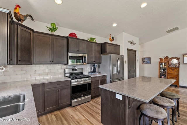2636 N Wrenley Ln, Post Falls, ID 83854 - kitchen featuring appliances with stainless steel finishes, light wood-style flooring, decorative backsplash, a center island, and lofted ceiling