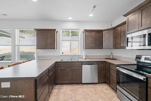 21714 S Lakeview Dr, Worley, ID 83876 - kitchen featuring stainless steel appliances, a peninsula, dark brown cabinets, recessed lighting, and stone finish floors