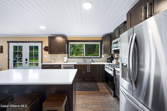 215 Gordon Dr, Priest Lake, ID 83856 - kitchen featuring stainless steel appliances, a breakfast bar, light countertops, dark brown cabinetry, and dark wood-type flooring