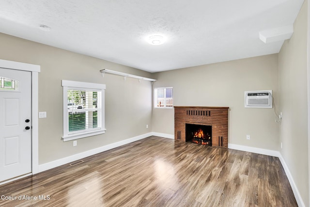 4204 N Jefferson St, Spokane, WA 99205 - unfurnished living room featuring wood finished floors, a fireplace, an AC wall unit, and a textured ceiling