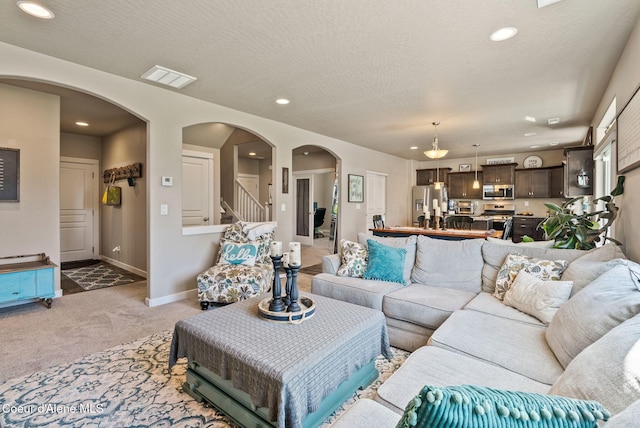 4483 N Connery Loop, Post Falls, ID 83854 - living room featuring light colored carpet, arched walkways, stairway, recessed lighting, and a textured ceiling
