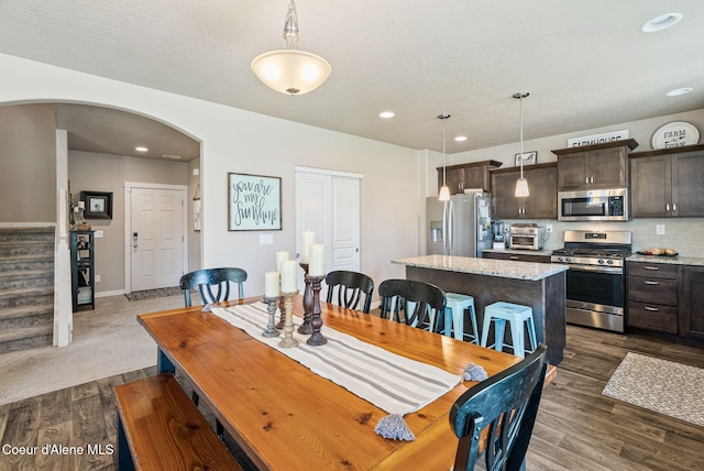 4483 N Connery Loop, Post Falls, ID 83854 - dining room with arched walkways, stairs, dark wood-style flooring, recessed lighting, and a textured ceiling
