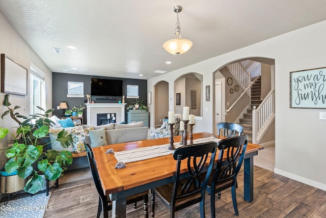4483 N Connery Loop, Post Falls, ID 83854 - dining space featuring dark wood-style flooring, stairway, a glass covered fireplace, recessed lighting, and arched walkways