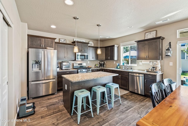 4483 N Connery Loop, Post Falls, ID 83854 - kitchen featuring appliances with stainless steel finishes, dark brown cabinets, dark wood-style floors, a kitchen island, and recessed lighting