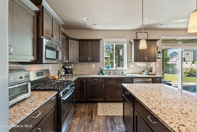 4483 N Connery Loop, Post Falls, ID 83854 - kitchen with appliances with stainless steel finishes, dark wood finished floors, dark brown cabinets, backsplash, and light stone countertops