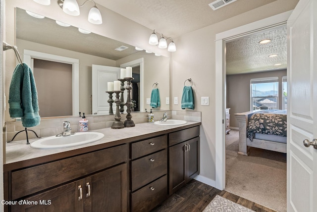 4483 N Connery Loop, Post Falls, ID 83854 - ensuite bathroom with double vanity, a textured ceiling, and wood finished floors