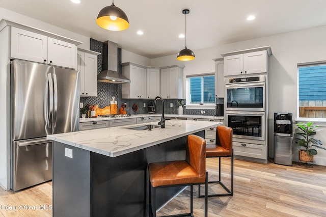 2119 E Lakeside Ave, Coeur Dalene, ID 83814 - kitchen with wall chimney exhaust hood, appliances with stainless steel finishes, decorative backsplash, light stone counters, and pendant lighting