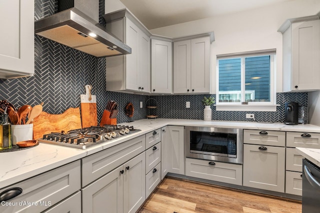 2119 E Lakeside Ave, Coeur Dalene, ID 83814 - kitchen with wall chimney range hood, appliances with stainless steel finishes, decorative backsplash, and light stone countertops