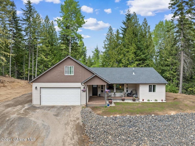 12671 E Trout Pond Rd, Athol, ID 83801 - view of front of home with covered porch, an attached garage, dirt driveway, and a shingled roof