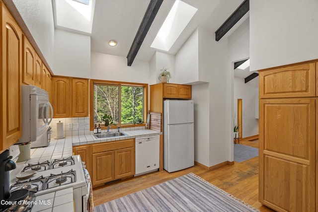 23388 N Teddy Loop, Rathdrum, ID 83858 - kitchen with a skylight, white appliances, tile counters, high vaulted ceiling, and tasteful backsplash