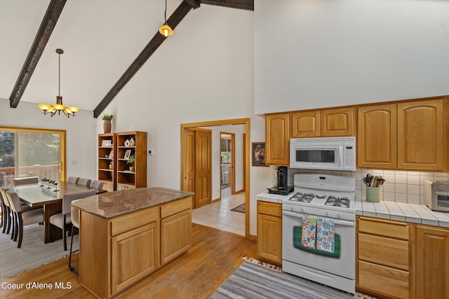 23388 N Teddy Loop, Rathdrum, ID 83858 - kitchen featuring white appliances, a chandelier, high vaulted ceiling, tile countertops, and light wood-style flooring