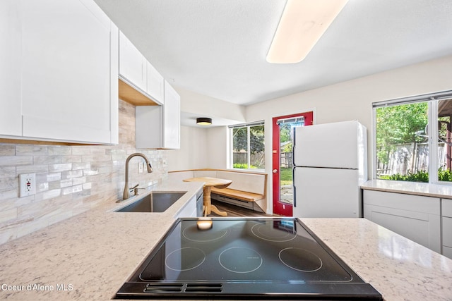 628 E Timber Ln, Coeur Dalene, ID 83815 - kitchen featuring freestanding refrigerator, decorative backsplash, white cabinetry, light stone countertops, and cooktop