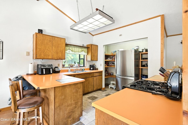 1655 Gun Club Rd, Sagle, ID 83860 - kitchen featuring freestanding refrigerator, a peninsula, brown cabinets, a kitchen bar, and light countertops