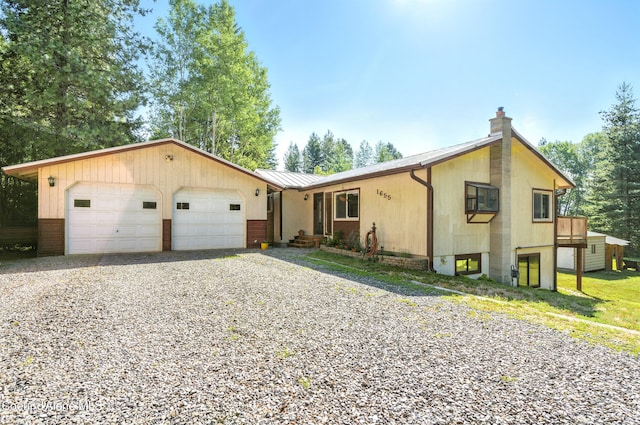 1655 Gun Club Rd, Sagle, ID 83860 - view of front facade with a chimney, an attached garage, driveway, a metal roof, and a standing seam roof