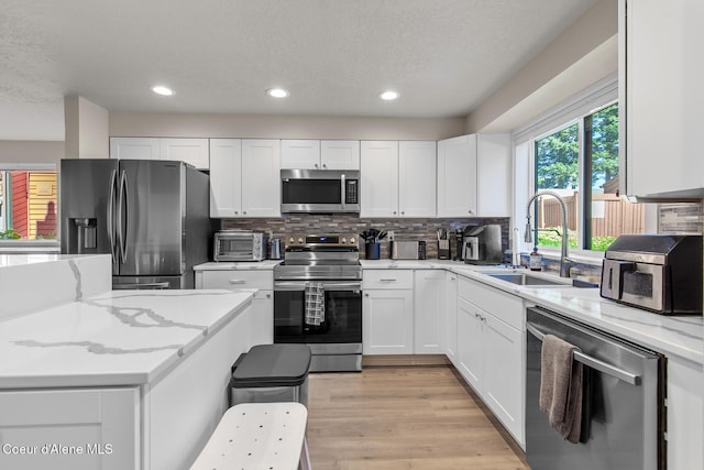 5299 W Green Ct # 23, Rathdrum, ID 83858 - kitchen with stainless steel appliances, white cabinetry, recessed lighting, backsplash, and light stone countertops