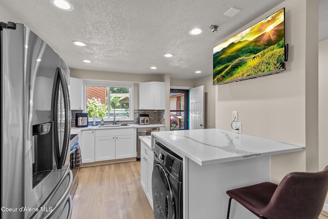 5299 W Green Ct # 23, Rathdrum, ID 83858 - kitchen featuring appliances with stainless steel finishes, washer / clothes dryer, light stone countertops, a textured ceiling, and light wood-style flooring