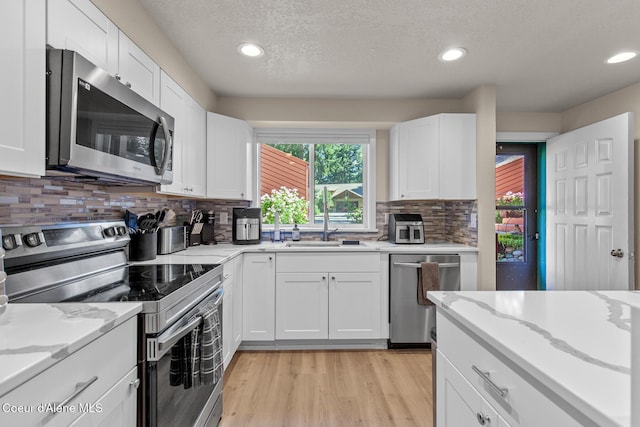5299 W Green Ct # 23, Rathdrum, ID 83858 - kitchen featuring appliances with stainless steel finishes, white cabinetry, light wood-type flooring, a textured ceiling, and recessed lighting