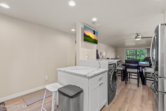 5299 W Green Ct # 23, Rathdrum, ID 83858 - kitchen featuring freestanding refrigerator, light stone counters, washer / dryer, light wood finished floors, and white cabinetry