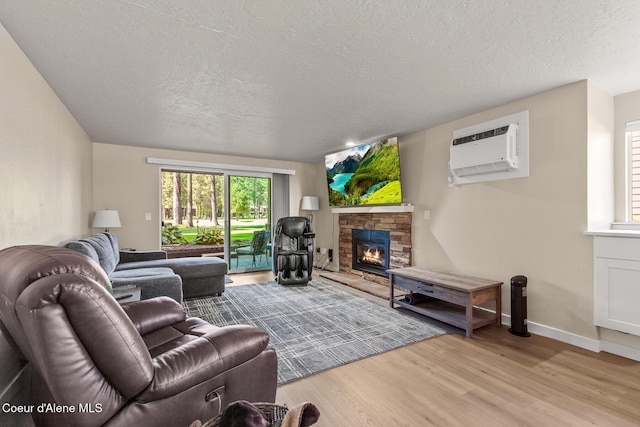 5299 W Green Ct # 23, Rathdrum, ID 83858 - living area featuring a wall unit AC, a fireplace, wood finished floors, and a textured ceiling