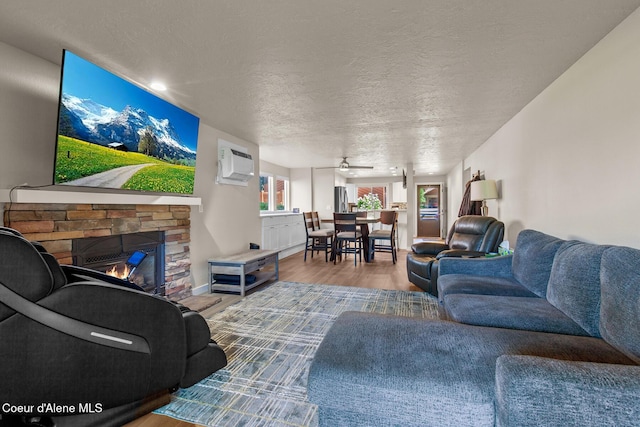 5299 W Green Ct # 23, Rathdrum, ID 83858 - living area featuring wood finished floors, a fireplace, a textured ceiling, ceiling fan, and a wall mounted AC