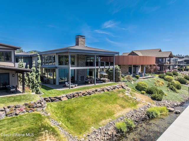 1758 W Bellerive Ln, Coeur Dalene, ID 83814 - back of house with a chimney, a patio area, a yard, and a balcony