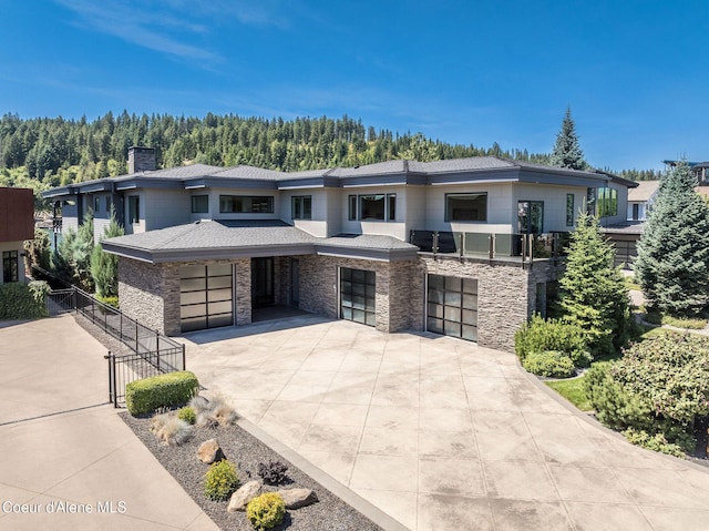 1758 W Bellerive Ln, Coeur Dalene, ID 83814 - prairie-style house with driveway, a garage, a chimney, stone siding, and a forest view