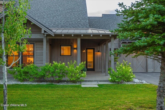 428 W Beach Ct, Dover, ID 83825 - view of front of house featuring roof with shingles, board and batten siding, a front yard, covered porch, and a garage