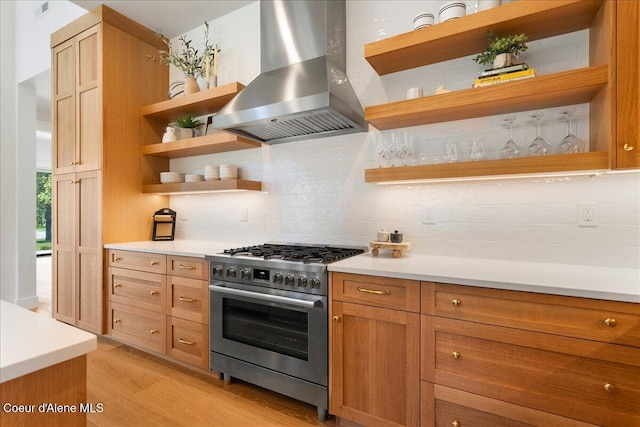 428 W Beach Ct, Dover, ID 83825 - kitchen with wall chimney range hood, stainless steel range with gas cooktop, open shelves, light wood finished floors, and backsplash