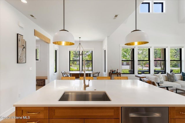 428 W Beach Ct, Dover, ID 83825 - kitchen with stainless steel dishwasher, open floor plan, brown cabinetry, light countertops, and decorative light fixtures