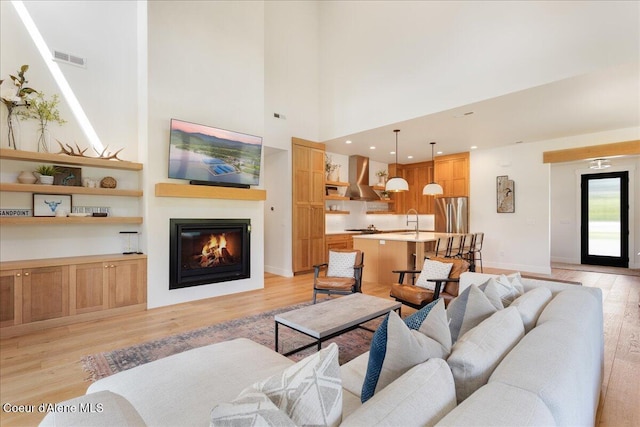 428 W Beach Ct, Dover, ID 83825 - living room featuring light wood finished floors, a glass covered fireplace, and a towering ceiling