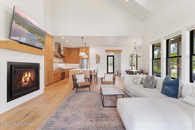 428 W Beach Ct, Dover, ID 83825 - living area with light wood finished floors, high vaulted ceiling, a lit fireplace, a chandelier, and recessed lighting