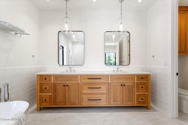 428 W Beach Ct, Dover, ID 83825 - full bathroom featuring tile walls, double vanity, a freestanding tub, a wainscoted wall, and tile patterned flooring