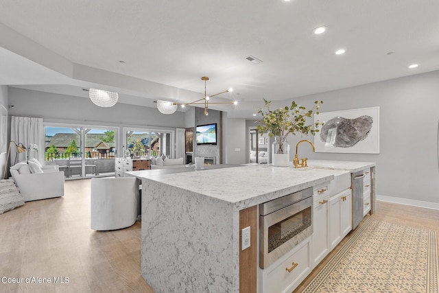 4732 S Arrow Point Dr # 304, Harrison, ID 83833 - kitchen featuring stainless steel appliances, open floor plan, white cabinetry, light wood-style flooring, and light stone counters