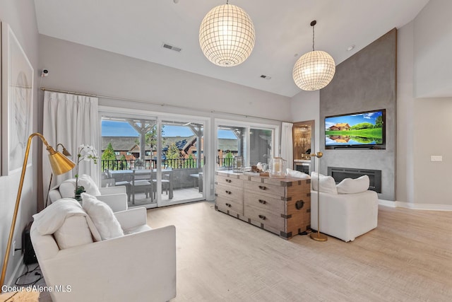4732 S Arrow Point Dr # 304, Harrison, ID 83833 - living room with light wood finished floors, a high ceiling, a chandelier, and a large fireplace
