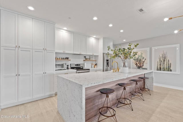 4732 S Arrow Point Dr # 304, Harrison, ID 83833 - kitchen featuring stainless steel appliances, white cabinetry, recessed lighting, light stone countertops, and a spacious island